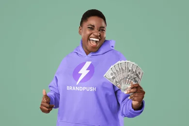 A woman in a BrandPush hoodie holding a fan of dollar bills