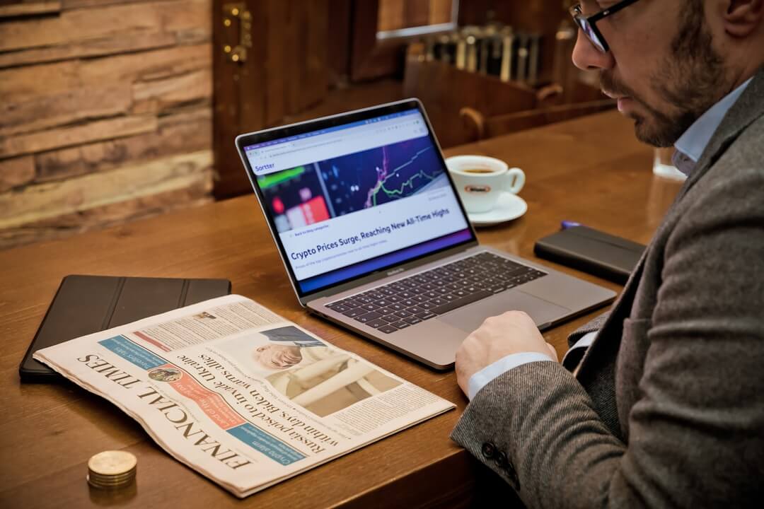 a man sitting at a table with a laptop and a cup of coffee