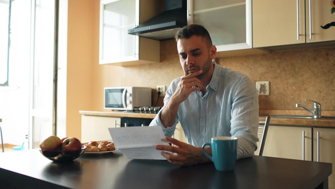 Person reviewing documents with calculator and laptop.