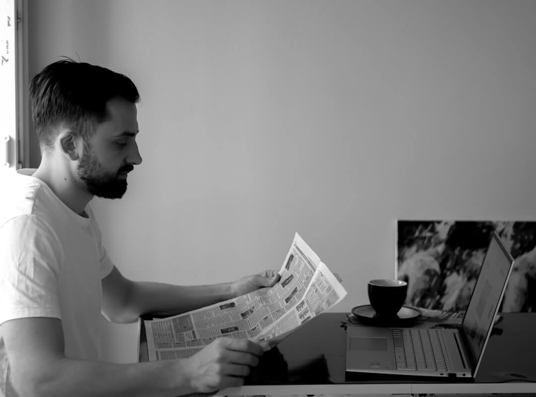 a man reading a newspaper while wearing glasses