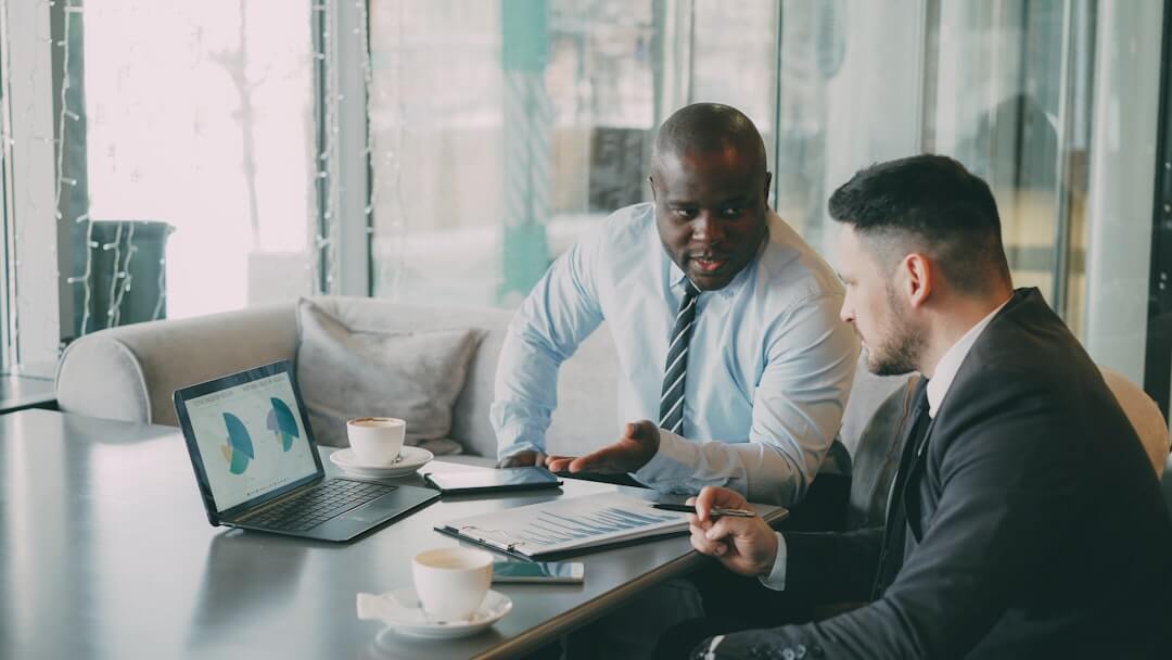 Two colleagues discussing work at a desk.