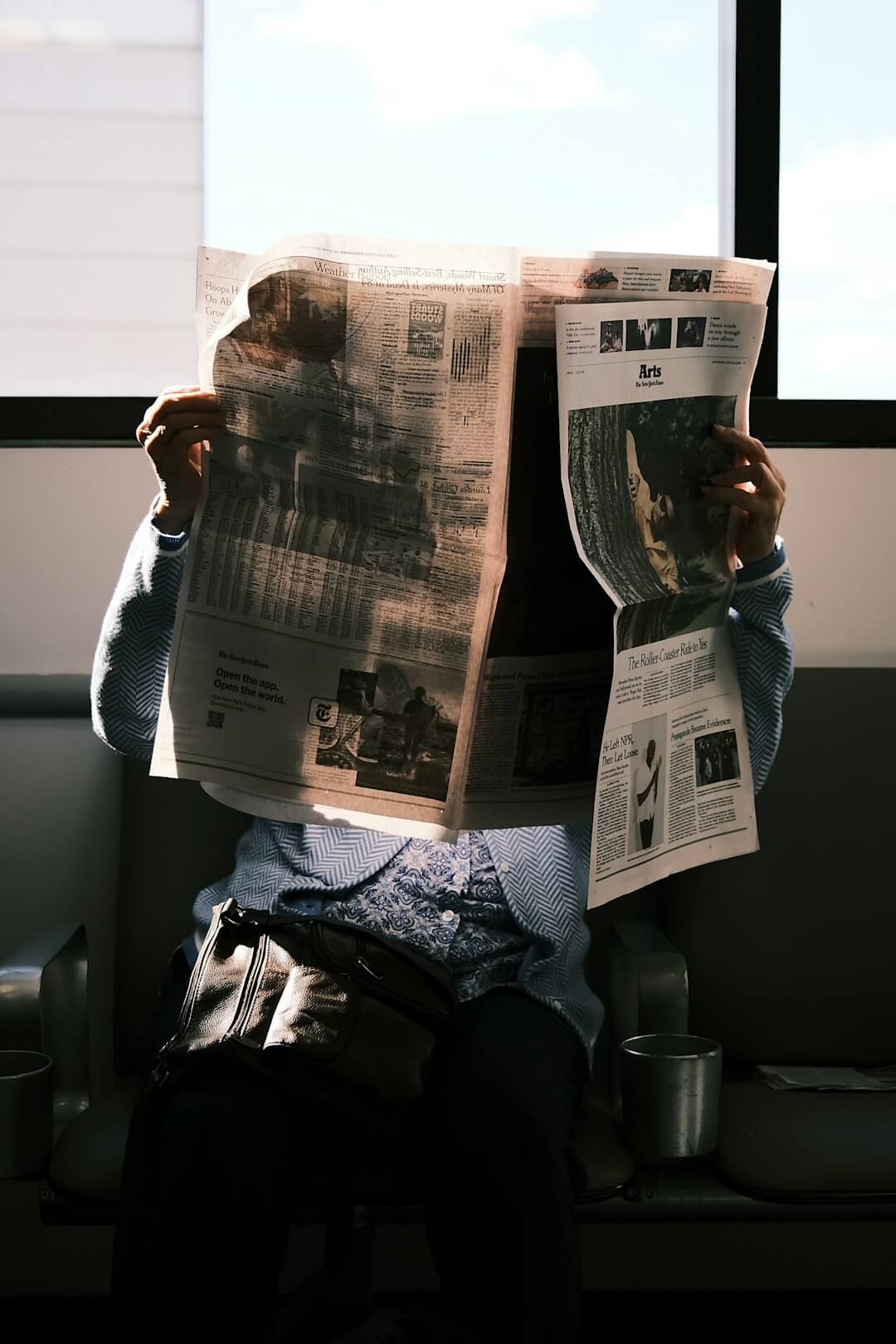 a man reading a newspaper while wearing glasses