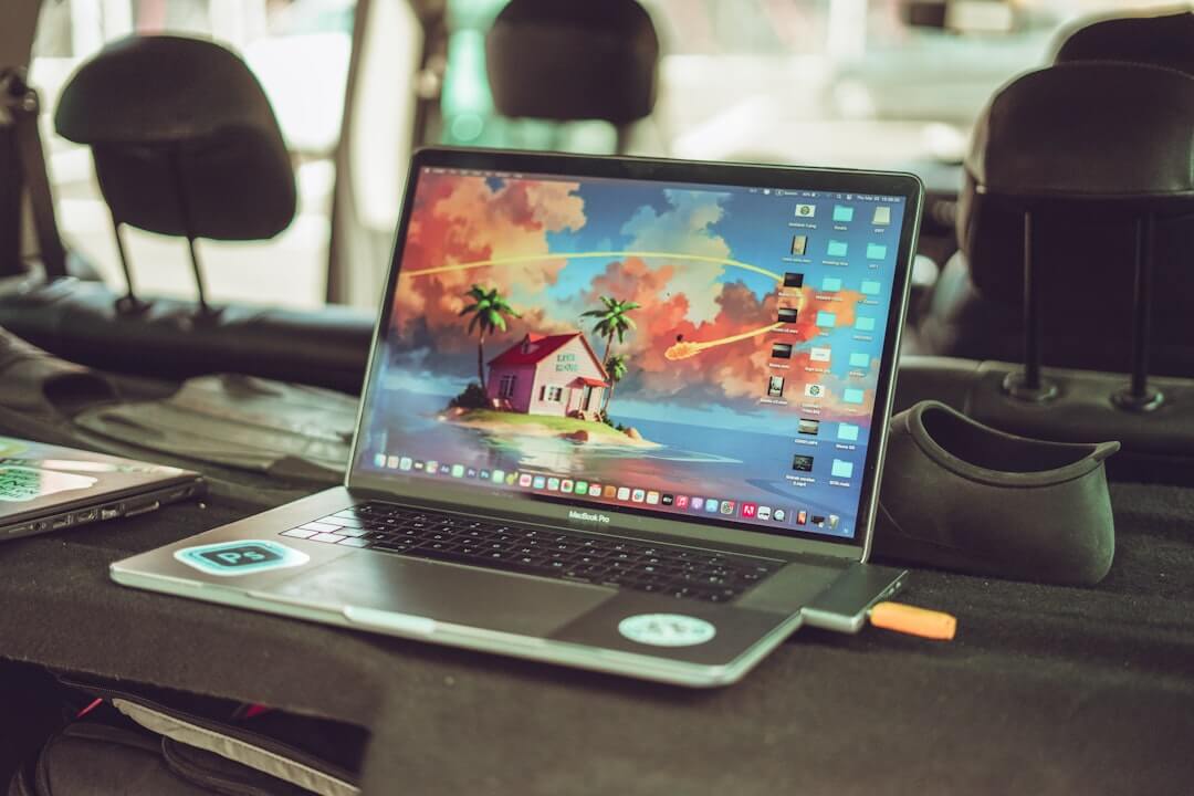 black and gray laptop computer near black wireless game controller on wooden table