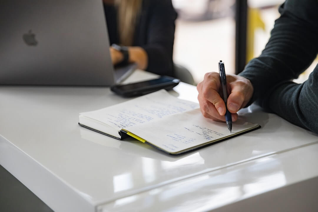 Person reviewing documents with calculator and laptop.