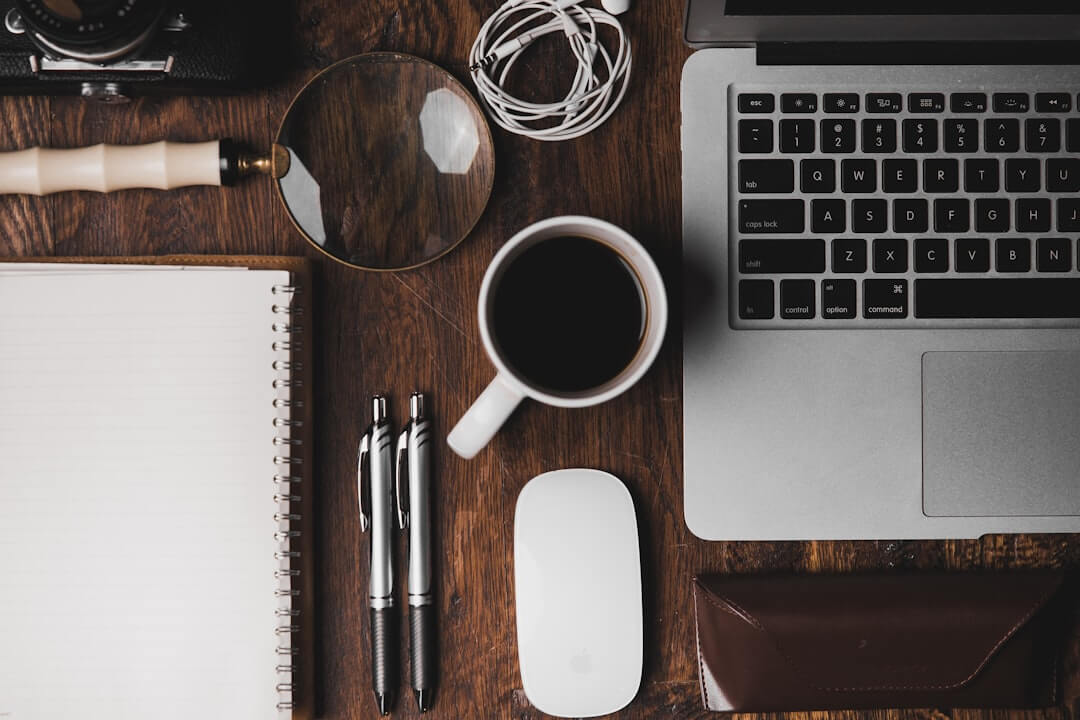 MacBook Pro, white ceramic mug,and black smartphone on table
