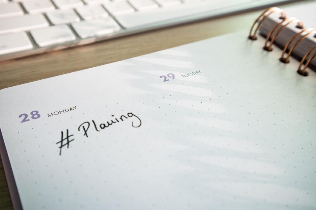 a notepad with a planner and a keyboard in the background