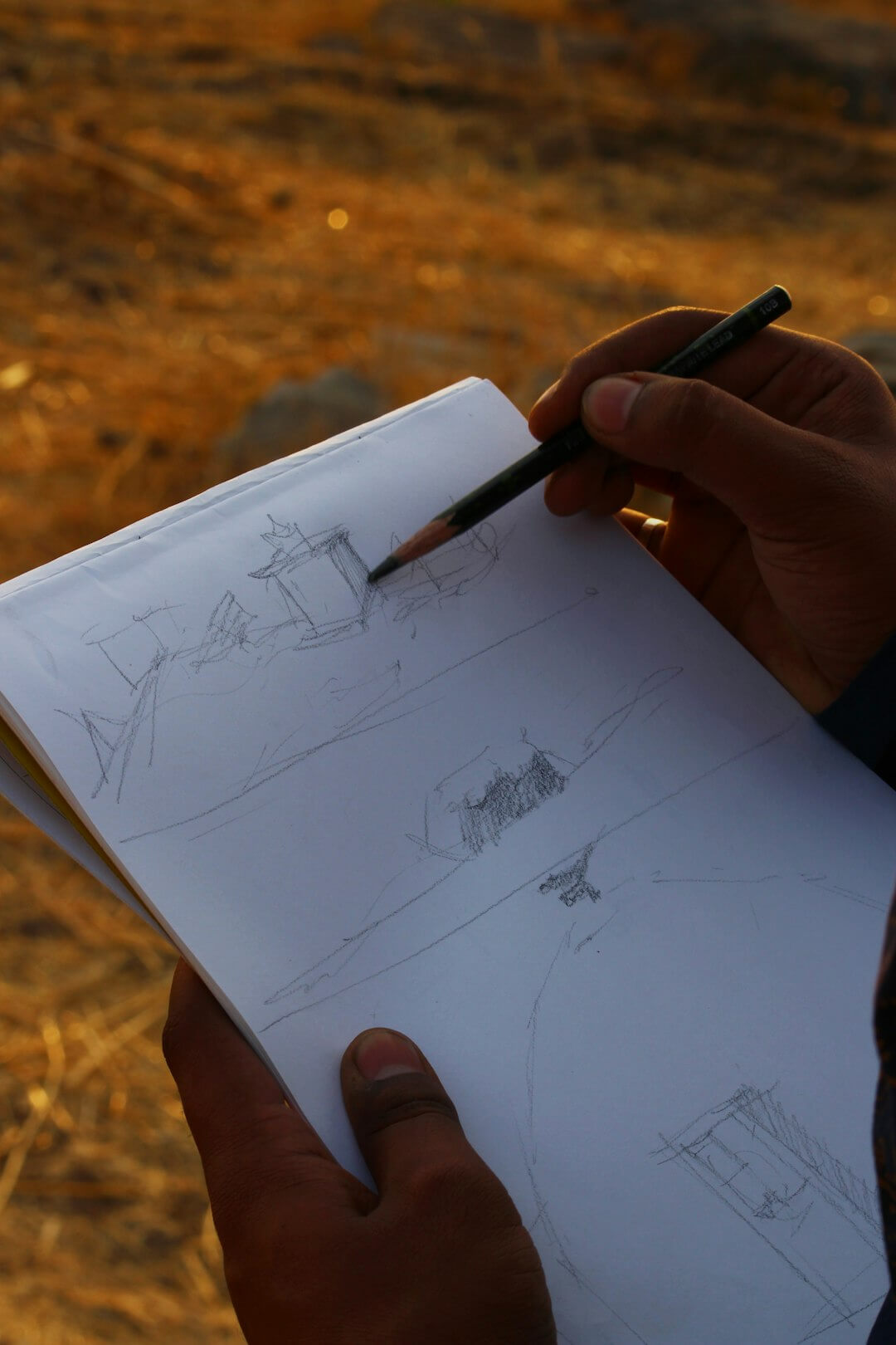 a person holding a pen and drawing on a piece of paper