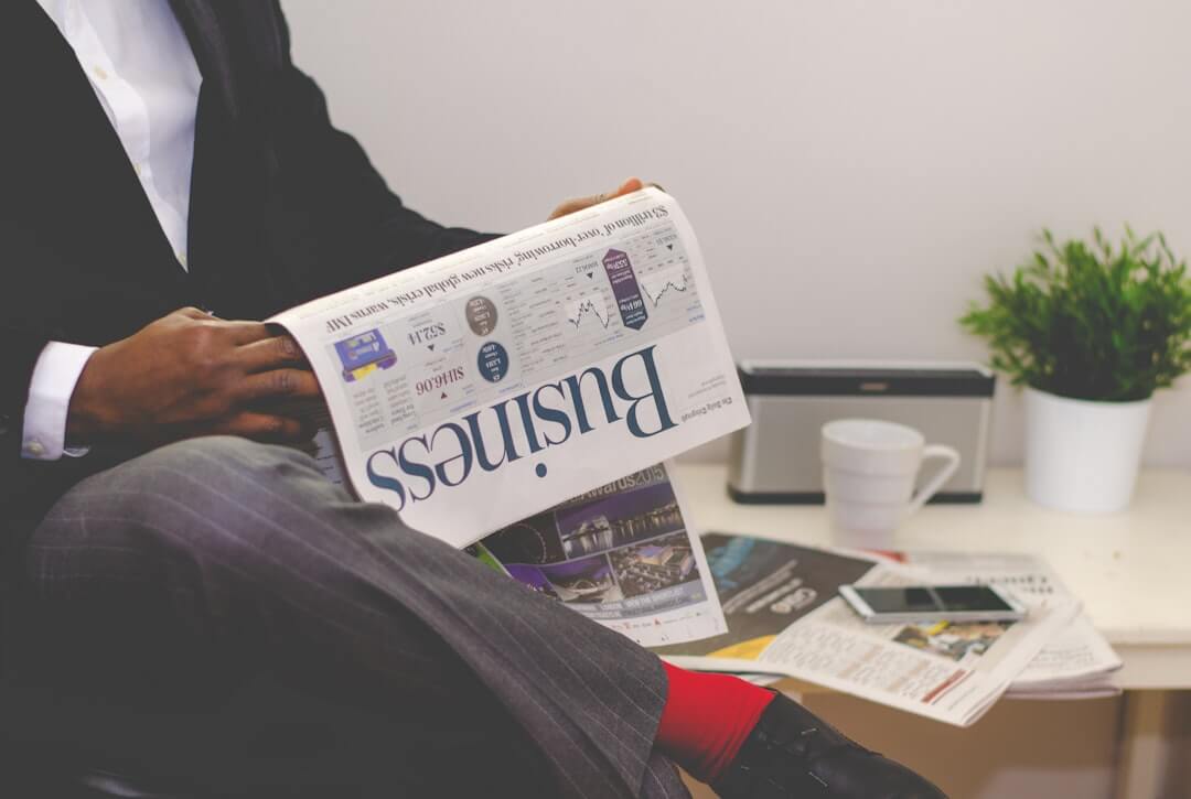 person wearing suit reading business newspaper