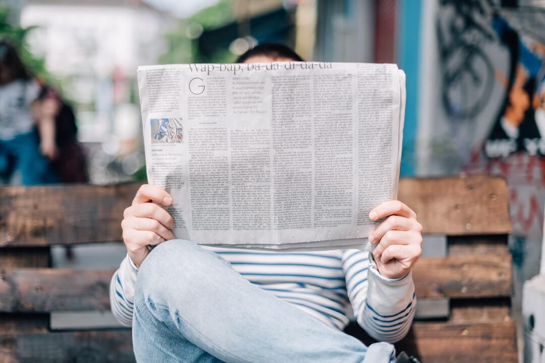 a person reading a newspaper with a cup of coffee