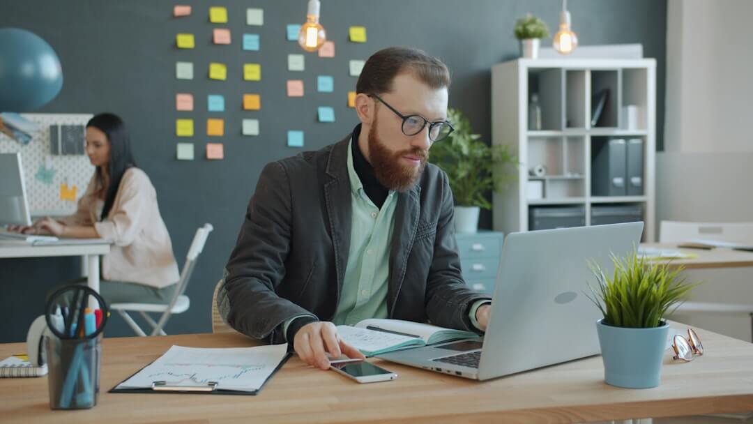 Laptop with code, headphones, phone, and mouse on desk.
