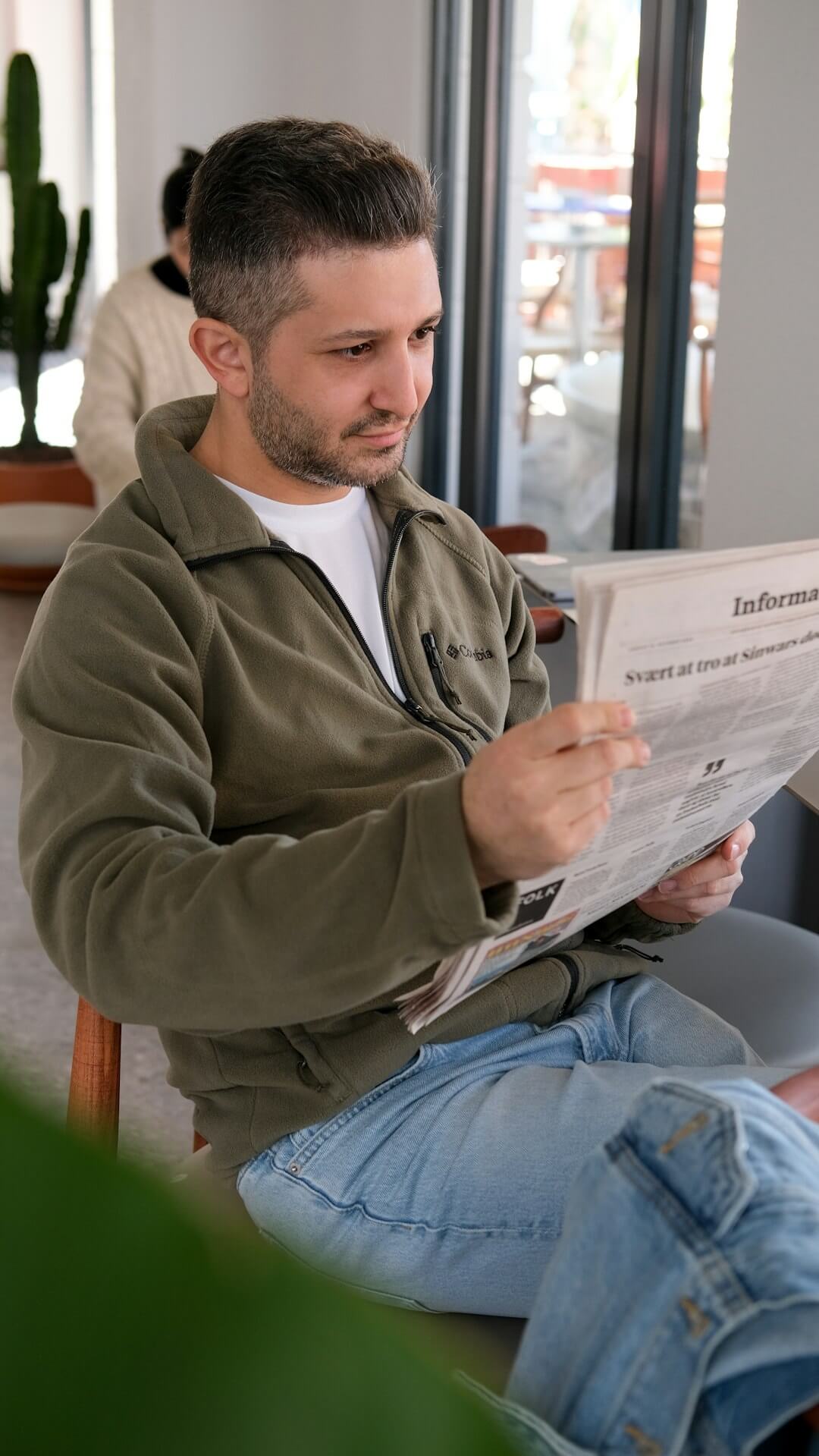 a man sitting on a couch reading a newspaper