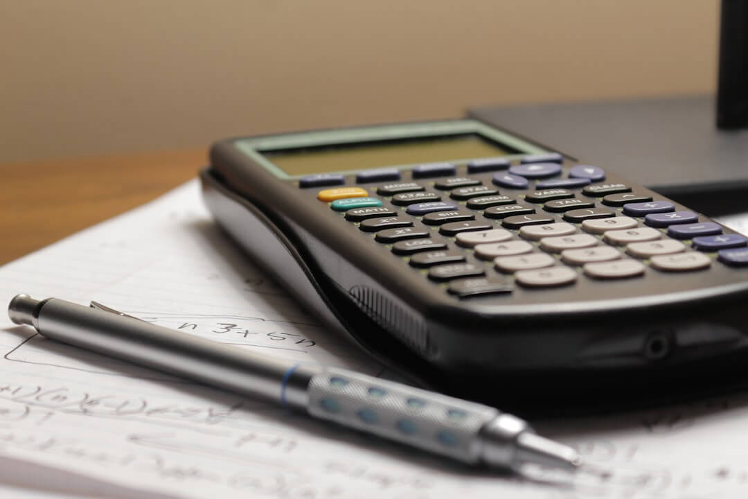 black calculator beside black pen on white printer paper