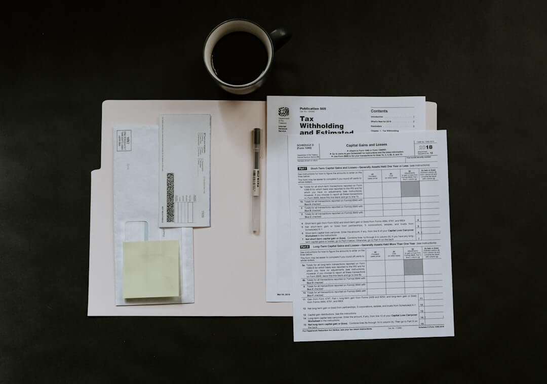 Tax forms with calculator and pen on dark surface