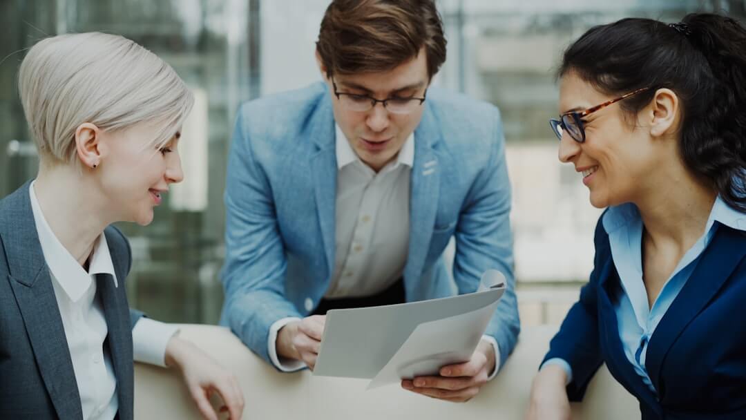 A person writing on a notebook with a laptop in the background
