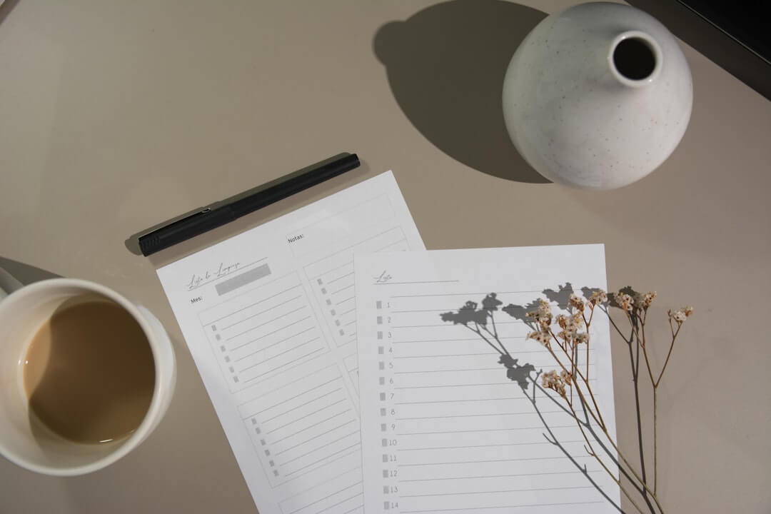 Person writing on clipboard at desk with laptop.