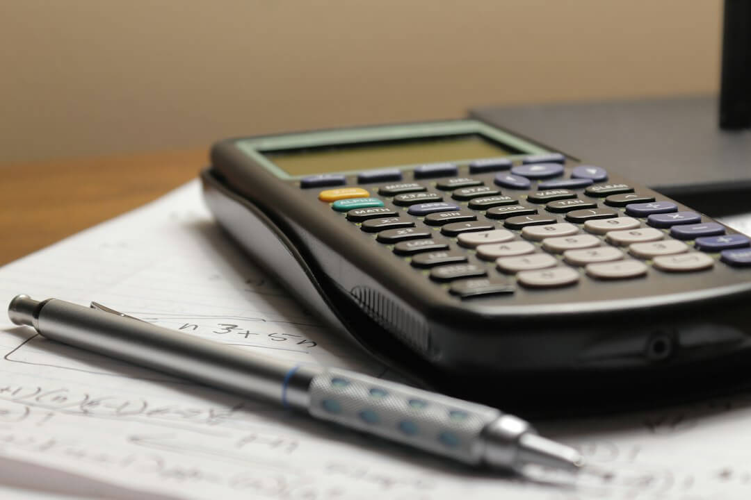black and silver calculator beside black pen