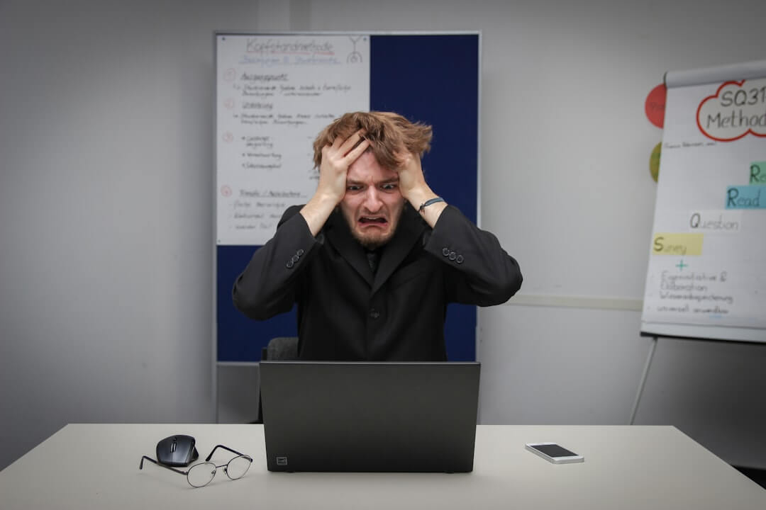 man in blue dress shirt holding silver macbook