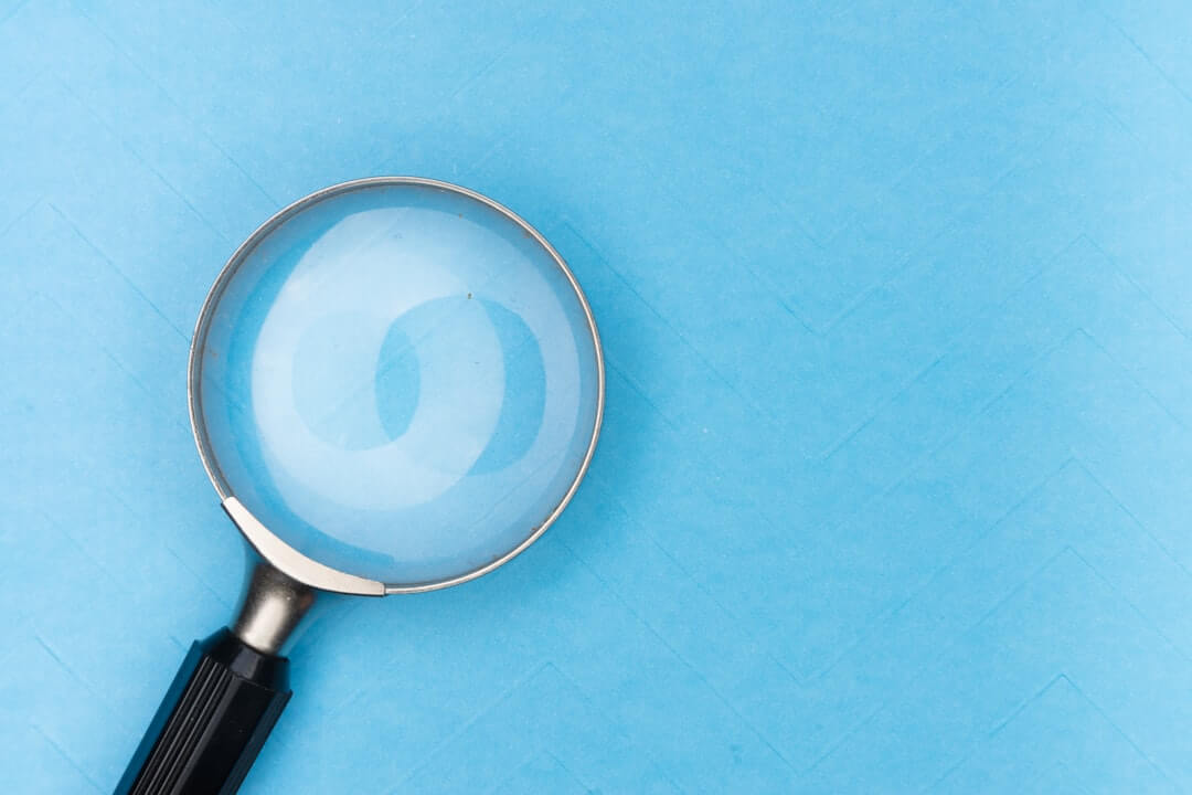 Magnifying glass sits near a laptop on a table.