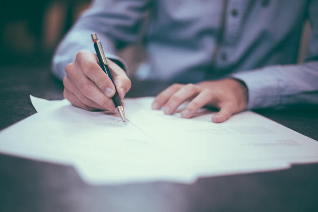 person writing on white form paper